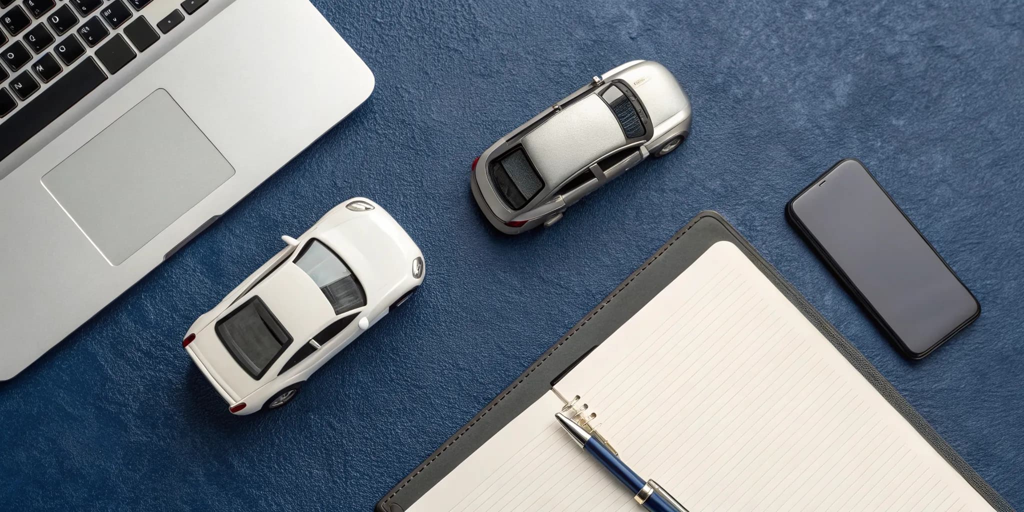 Toy cars on a desk with a laptop and notebook for researching traffic accident legal advice.